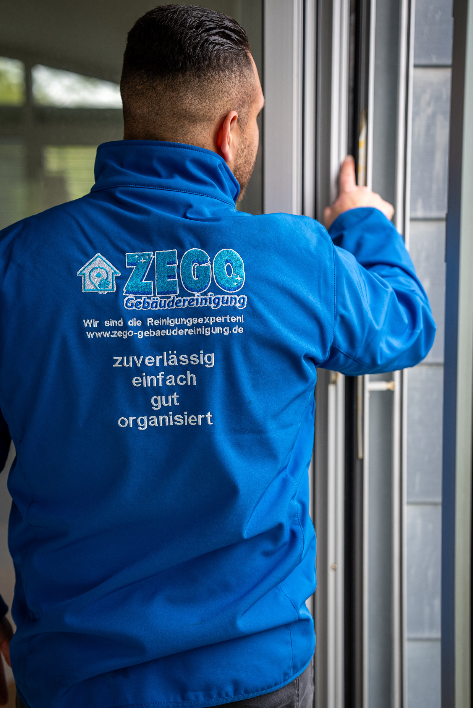 Mitarbeiter von ZEGO in blauer Arbeitsjacke bei der Übergabe an der Tür