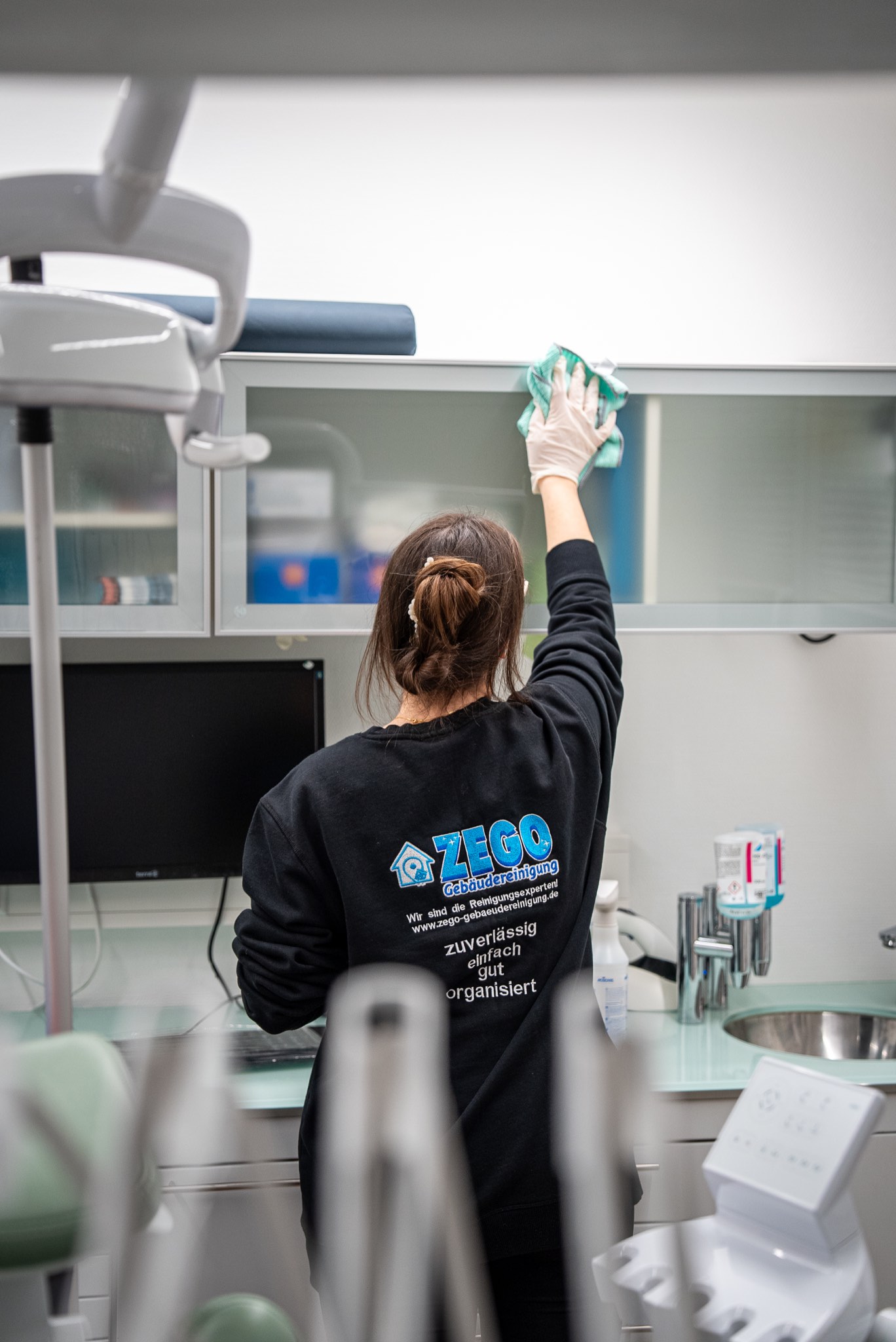 Mitarbeiterin von ZEGO reinigt die Ablagen in einer Zahnarztpraxis