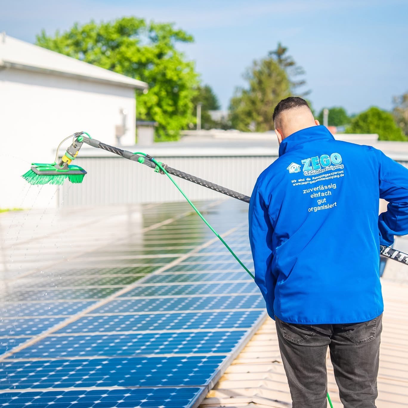Mitarbeiter von ZEGO reinigt Solarmodule mit Wasserbürste